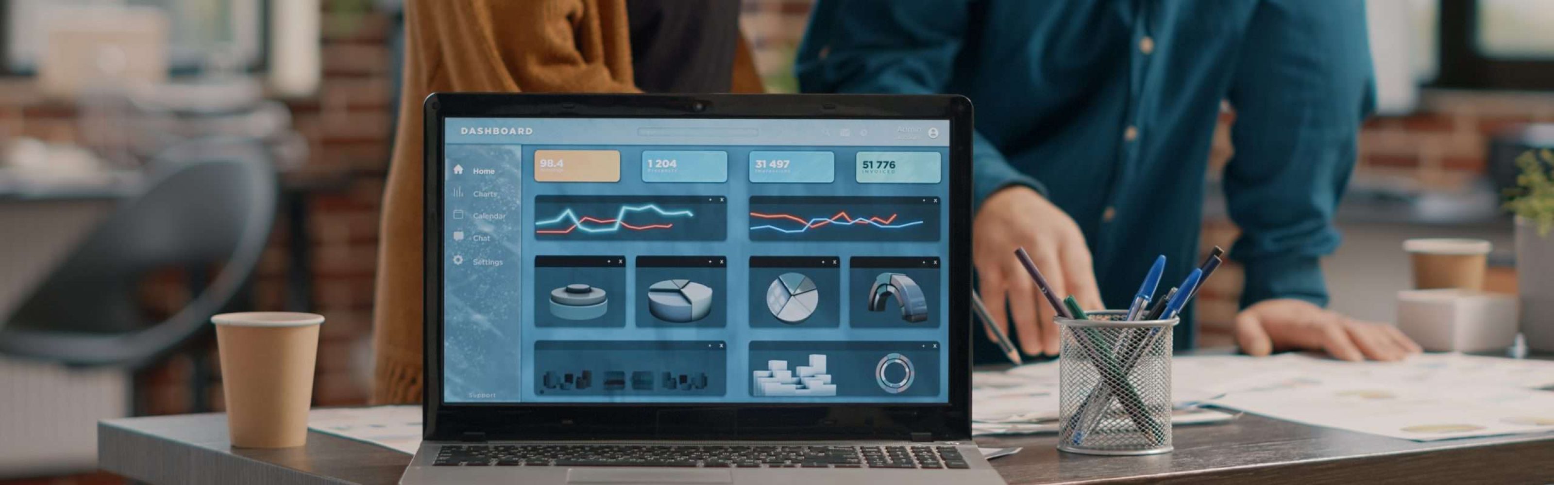 Close up of modern laptop with rate charts on display while man and woman working on business project design. Computer screen with data chart information and finance analysis on desk.