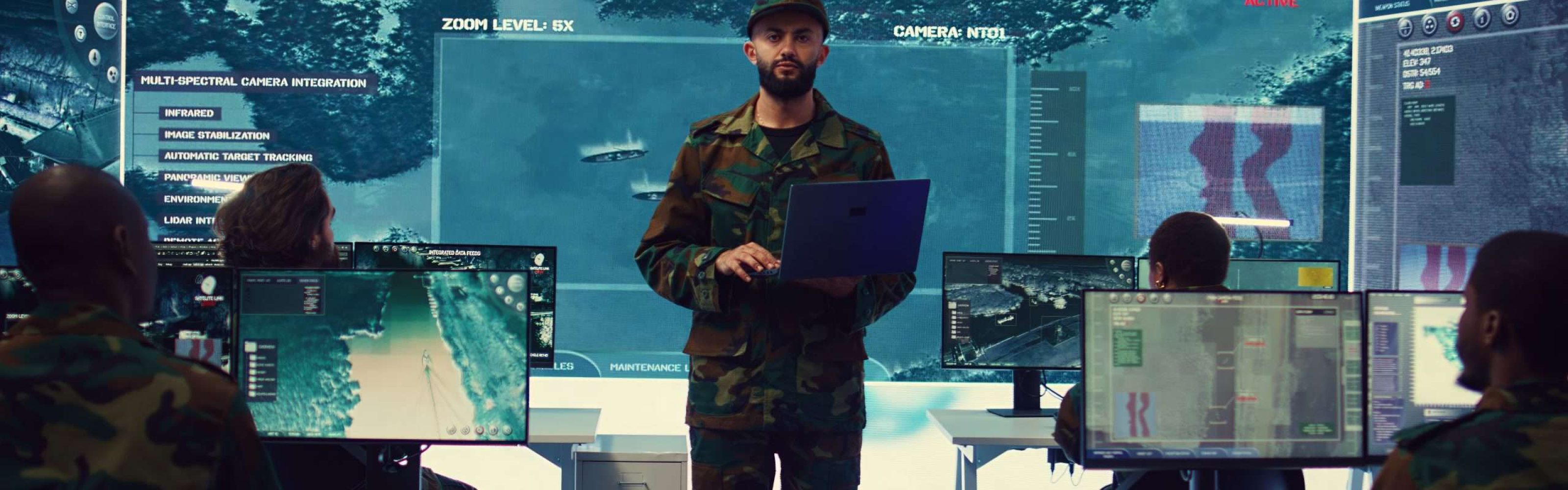 Special operations soldier allocating resources to different units based on mission needs, examines strategic data on a big screen in military control center. Marine corps troops. Camera B.